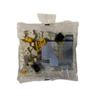 Plastic polybag containing assorted white, yellow, and black building bricks with instruction sheet inside.