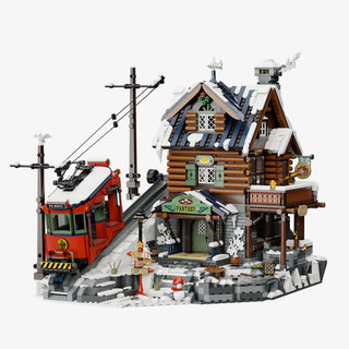 Modular building set featuring a log cabin with snow-covered roof, red train car, utility poles, and small accessories on a g