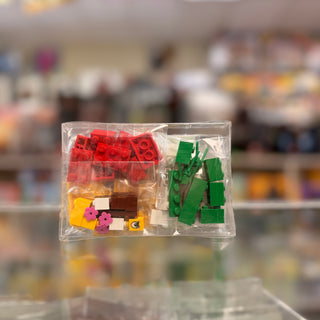 Polybag containing red, yellow, green, and brown plastic building blocks with small pink flower pieces and a printed instruct