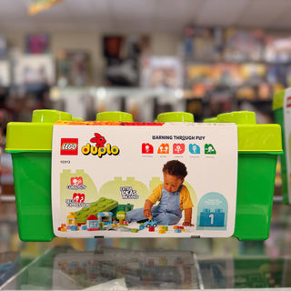 LEGO Duplo 10913 brick box with green handles and beige label showing toddler playing with colorful blocks.