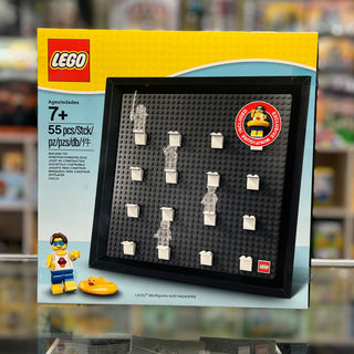 Black framed display case with dark studs and white pegs holding LEGO minifigures, shown on yellow packaging box.