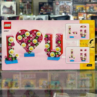 LEGO set 40867 featuring buildable flower arrangements spelling "LOVE" in pink, yellow, and green flowers with blue bases.