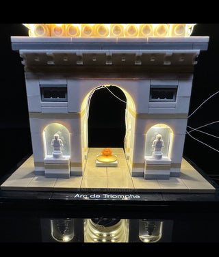 LEGO Arc de Triomphe set illuminated with warm white LED lights on architectural details and minifigure alcoves.