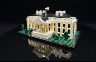 White House LEGO set with illuminated windows and roofline lights on black display base.