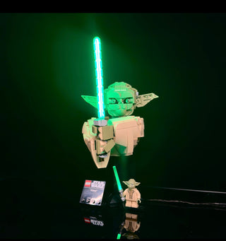 LEGO Yoda bust with illuminated cyan lightsaber, displayed with minifigure and instruction box below.