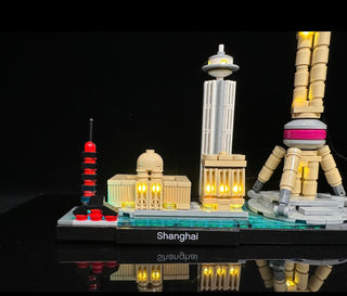 LEGO Shanghai skyline architecture set with illuminated yellow and red lights throughout buildings and pagoda structures on b