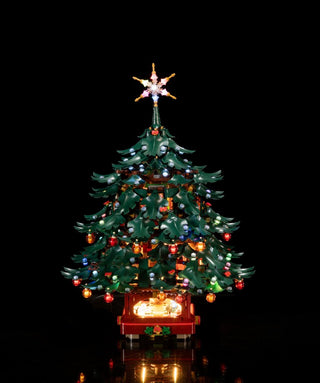 Illuminated LEGO Christmas tree with green branches, multicolored ornaments, star topper, and glowing base unit against black