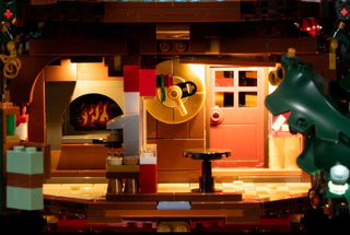 LEGO Christmas house interior with lit fireplace, door, windows, and warm lighting throughout the scene.