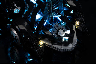 Black LEGO Batmobile with blue LED lighting on canopy and yellow headlights illuminated against dark background.