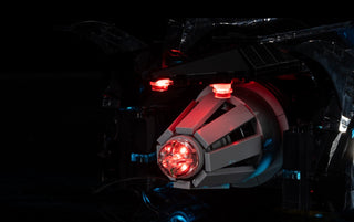LEGO Batmobile with red and blue LED lights illuminated on dark background.