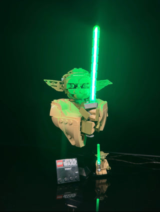 LEGO Yoda bust with illuminated green lightsaber and control unit, displayed with matching minifigure.