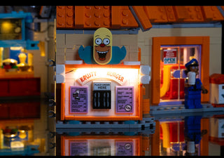 Illuminated LEGO Krusty Burger storefront with lit sign, Krusty character head, and glowing interior details.