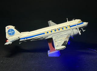 LEGO Douglas DC-3 Pan Am airliner with illuminated cabin windows and landing lights on display stand.
