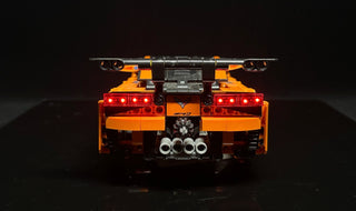 Black and orange LEGO Corvette ZR1 with illuminated red tail lights, viewed from rear against dark background.
