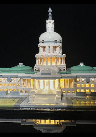 LEGO Capitol Building model with internal yellow LED lights illuminating the dome, rotunda, and wings against a black backgro