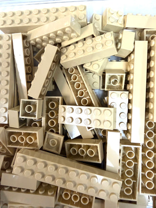 Assorted tan and white LEGO bricks and plates of various sizes stacked together.