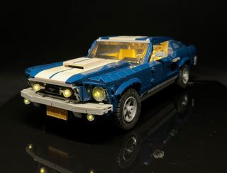 Blue and white LEGO Ford Mustang GT with yellow LED lights installed in headlights, interior, and bumper area.
