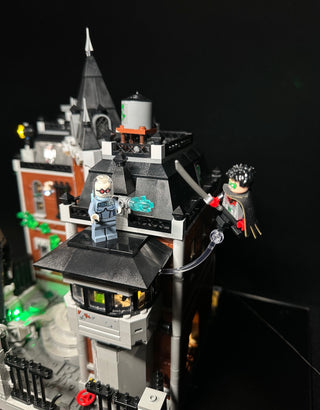 LEGO Arkham Asylum building set illuminated with colored LED lights on tower, minifigures, and base sections.