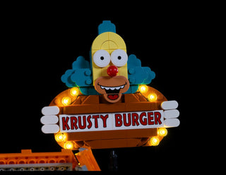 LEGO Krusty Burger set with illuminated yellow character head and orange LED lights on sign and structure.