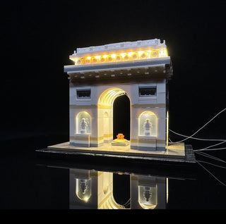 LEGO Arc de Triomphe set with warm white LED lights illuminating the roofline, archway, and side niches.