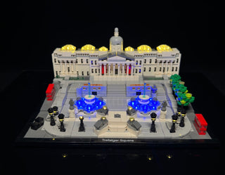LEGO Trafalgar Square set illuminated with yellow dome lights, blue fountain lights, and black base lights against dark backg