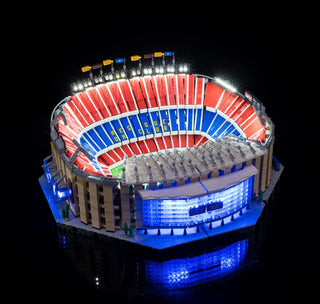 Illuminated LEGO Camp Nou stadium model with red, blue, and white lit seating sections and white floodlights around the top.