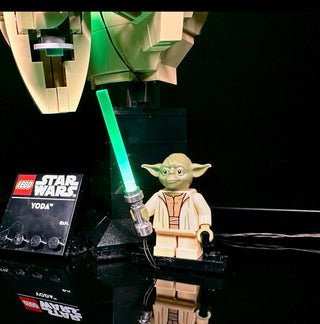 LEGO Yoda minifigure holding illuminated green lightsaber with connected LED lighting components and wiring.