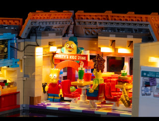 Illuminated LEGO Krusty Burger playset with warm yellow LED lights installed throughout the storefront and interior display a