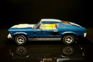 Blue and cream LEGO Ford Mustang GT with illuminated interior and headlights against a dark background.