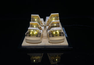 LEGO Sydney Opera House set with warm yellow LED lights illuminating the shell-shaped structures against a black background.