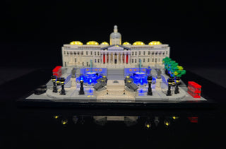 LEGO Trafalgar Square set illuminated with yellow dome lights, blue fountain lights, and red accent lights on black base.