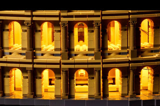 Tan and brown LEGO Colosseum structure with warm yellow LED lights illuminating arched doorways across two levels.