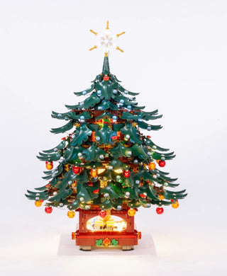 Green and red LEGO Christmas tree with illuminated ornaments, star topper, and glowing base against white background.