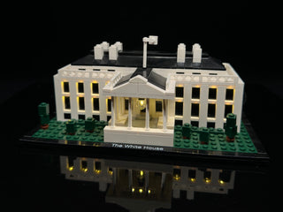 LEGO White House set with illuminated windows and exterior lights on black display base.
