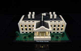 LEGO White House building with illuminated windows and interior lighting on display base.