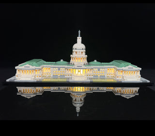 LEGO Capitol Building model illuminated with warm yellow LED lighting throughout the dome and facade against black background