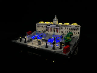Illuminated LEGO Trafalgar Square set featuring yellow rooftop lights, blue fountain lights, and warm accent lighting through