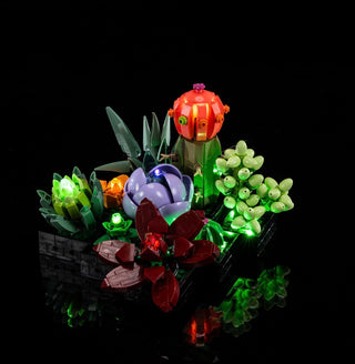 Illuminated LEGO succulent display with red, orange, purple, and green LED-lit plant pieces on black base.