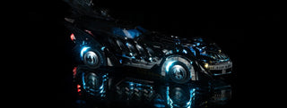 Black LEGO Batmobile with blue and red LED lighting illuminated on wheels, windows, and body details.
