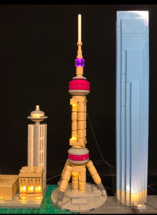 Illuminated LEGO Shanghai skyline display with lit tower structures and buildings against dark background.