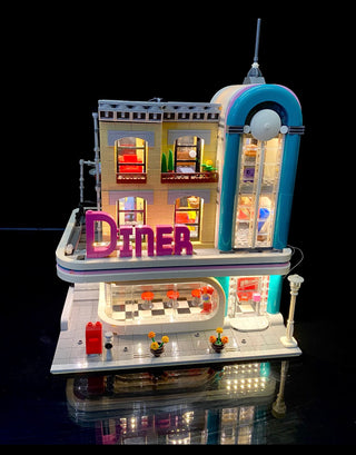 LEGO Downtown Diner building set with illuminated windows, purple "DINER" sign, and blue neon architectural details.