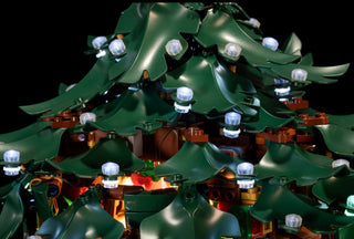 LED lighting kit with white and colored lights installed on green and brown LEGO Christmas tree structure.