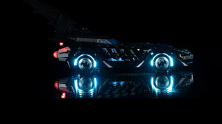 LEGO Batmobile with blue LED headlights and red tail lights illuminated against black background.