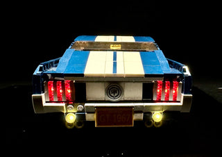LEGO Ford Mustang GT with illuminated red taillights and yellow headlights against black background.