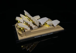 LEGO Sydney Opera House model with warm white LED lights illuminating the shell structures on a tan base.