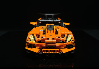 Orange LEGO Chevrolet Corvette ZR1 with illuminated headlights, taillights, and interior details, viewed from above against b