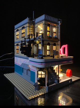 Illuminated LEGO Downtown Diner set with warm white window lights, neon pink signage, and street-level storefront display on 