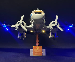 White and blue LEGO Douglas DC-3 Pan Am airliner with illuminated blue wing lights and yellow landing lights on dark display 