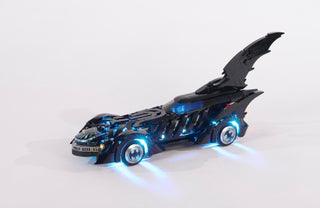 Black Batmobile with blue LED lights illuminated on wheels, body, and interior against white background.