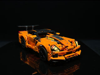 Orange and black LEGO Chevrolet Corvette ZR1 with illuminated headlights and body details against dark background.